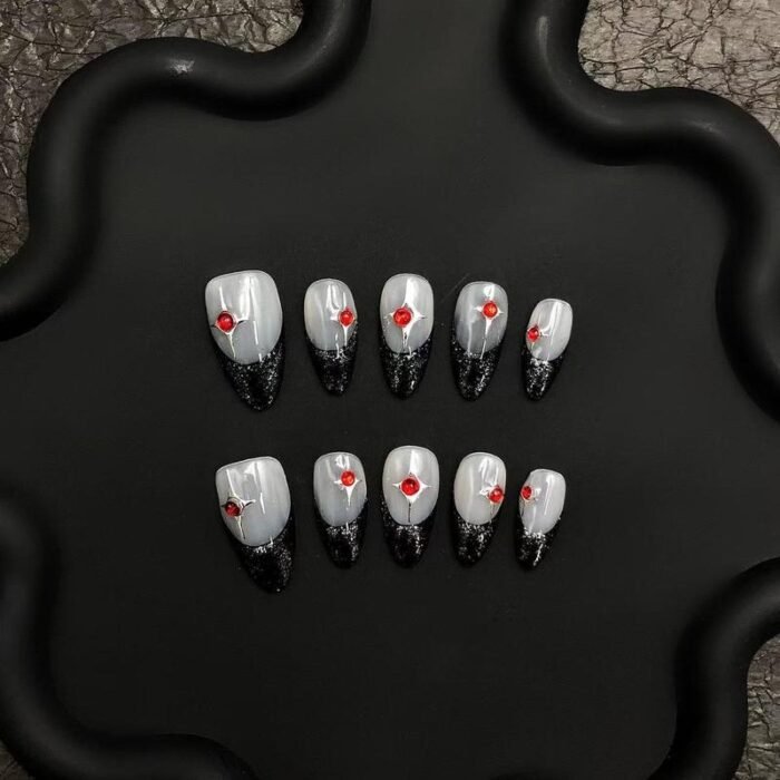 Close-up of red rhinestone details on grey and black glitter press-on nails