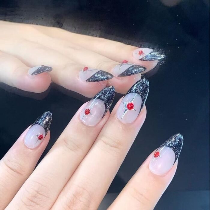 Model wearing grey and black glitter French press-on nails with red rhinestones
