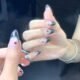 Lifestyle image of model wearing grey and black glitter press-on nails