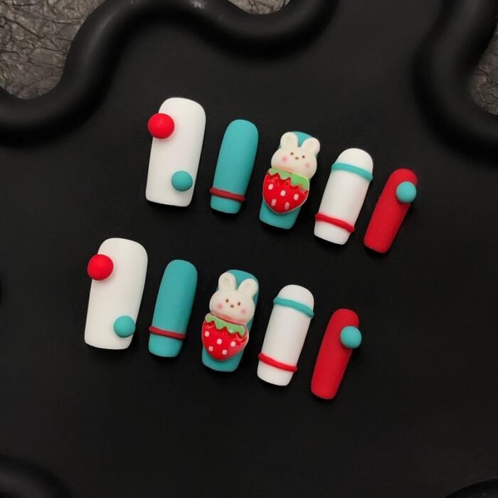 Side angle of Lavara handmade press-on nails showing 3D bunny and strawberry designs with teal and white accents