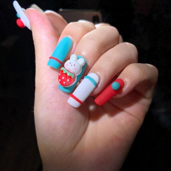 Model wearing Lavara cute bunny strawberry press-on nails with red, white, and teal colors
