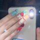 Model showcasing Lavara 3D bunny strawberry press-on nails with red, white, and teal patterns