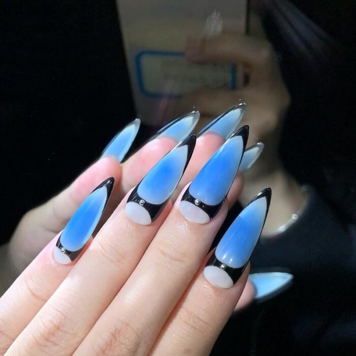 Model hand wearing Lavara futuristic blue black press-on nails with metal studs